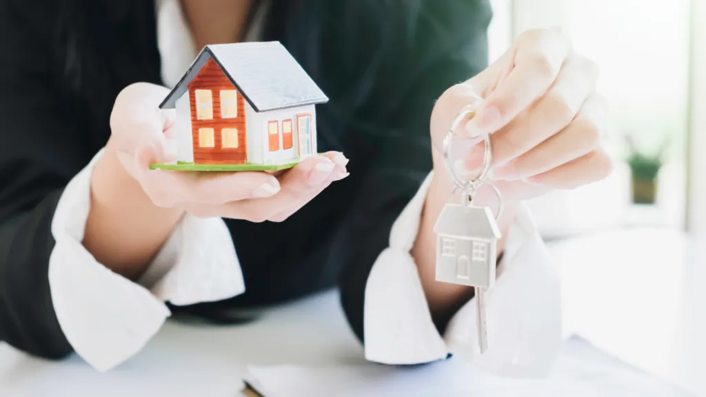 Woman holding a toy house and a key in her hands