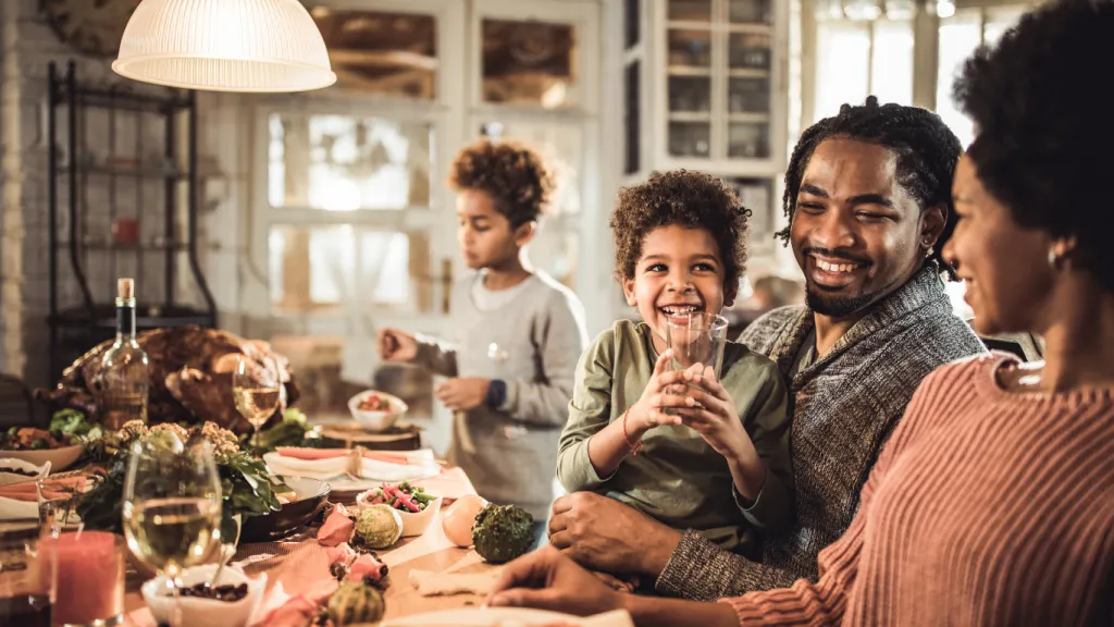 A family discussing a budget at the dining table, emphasizing the role of families in financial education for youth.