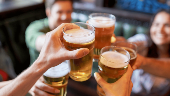 Grupo de amigos disfrutando de cervezas en un bar, representando el 30% destinado a deseos en la regla 50/30/20, que permite el gasto en entretenimiento y ocio.