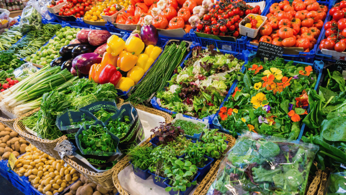 Mercado de frutas y verduras frescas, ilustrando la categoría de necesidades en la regla 50/30/20, que incluye gastos esenciales como la alimentación.