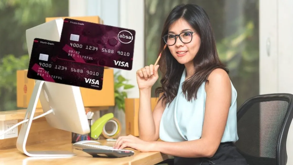 Woman smiling at computer looking at premium ABSA card