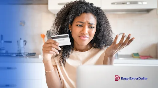 a woman looks sadly at the laptop screen while holding a credit card