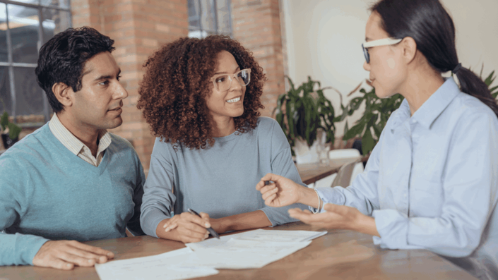 Asesor financiero conversando con una pareja sobre opciones para consolidar deudas, mostrando apoyo profesional y planificación financiera conjunta.