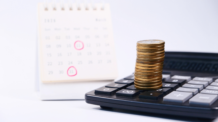 Calendar with payment reminders and coins stacked on a calculator, representing budgeting and BNPL planning versus SA Credit Cards.