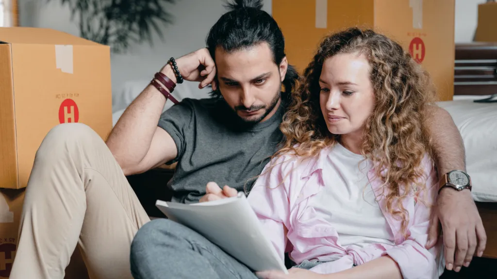 Young couple analyzing housing options, carefully reviewing documents to compare the pros and cons of buying vs. renting a home.