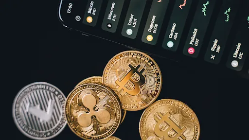 Cell phone on the table showing values ​​of cryptocurrencies and cryptocurrencies next to it