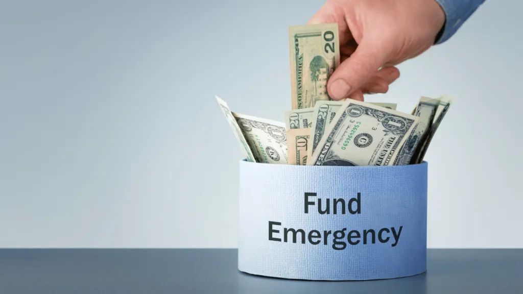 A hand placing cash into a jar labeled "Emergency Fund," representing the importance of financial planning and an Effective Budget in preparing for unexpected expenses.