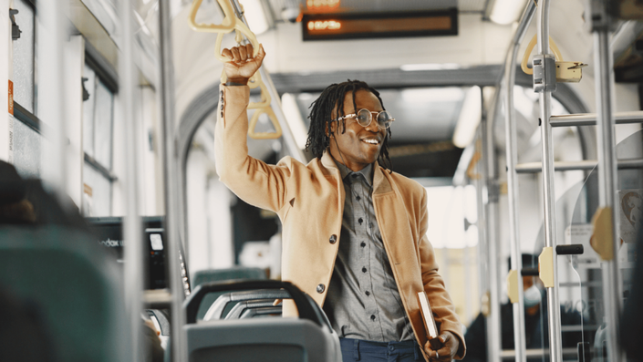 A person happily traveling on public transport, demonstrating how to save money on a tight budget by using affordable transport options.