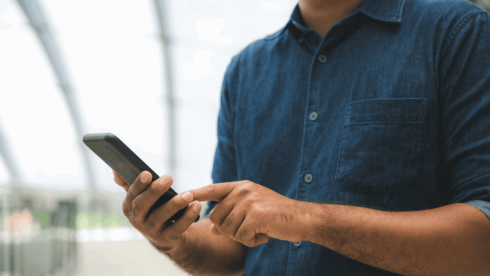 Una persona sostiene un smartphone, accediendo a su portafolio de inversiones seguras a través de una aplicación de finanzas fácil de usar.