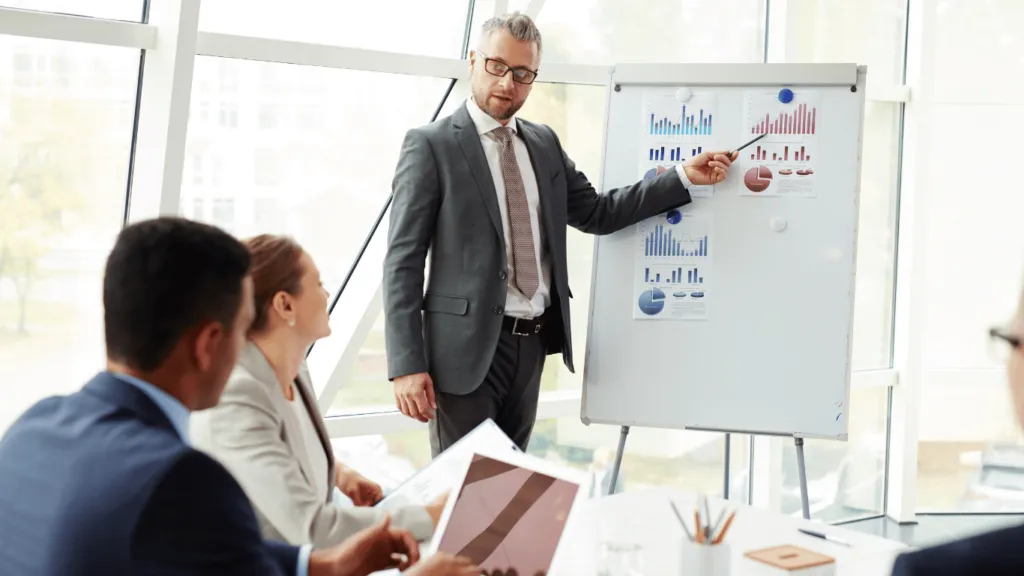 A group of professionals reviewing financial documents and graphs, discussing the Impact of Global Market on business strategies.