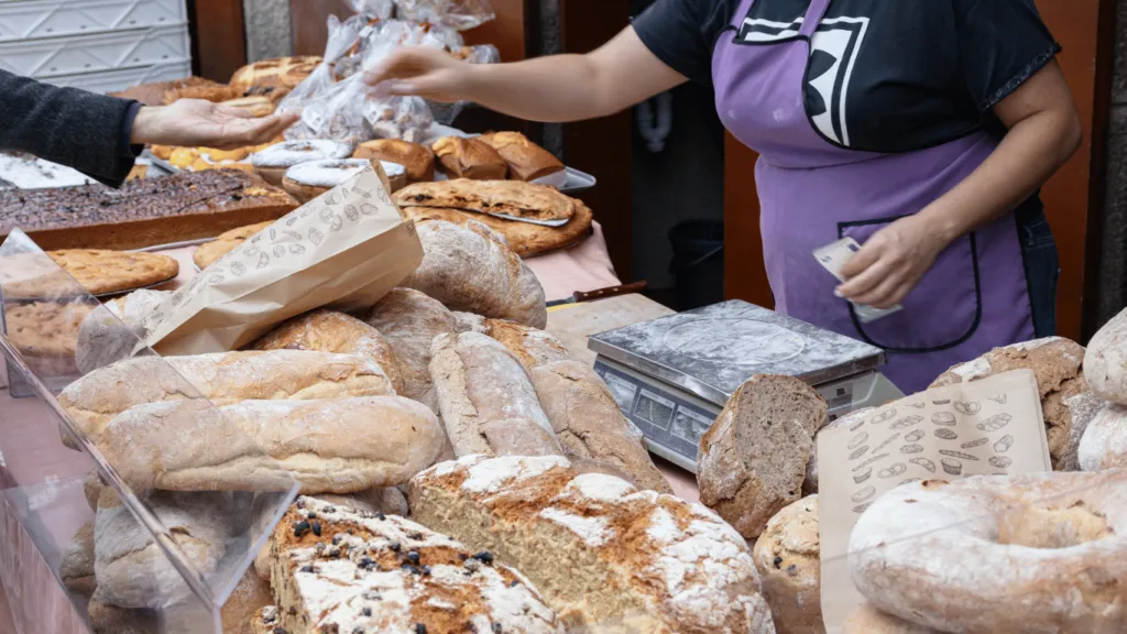  A local entrepreneur selling freshly baked goods at an outdoor market. This represents a practical way to start a business with little money by offering handmade or homemade products.