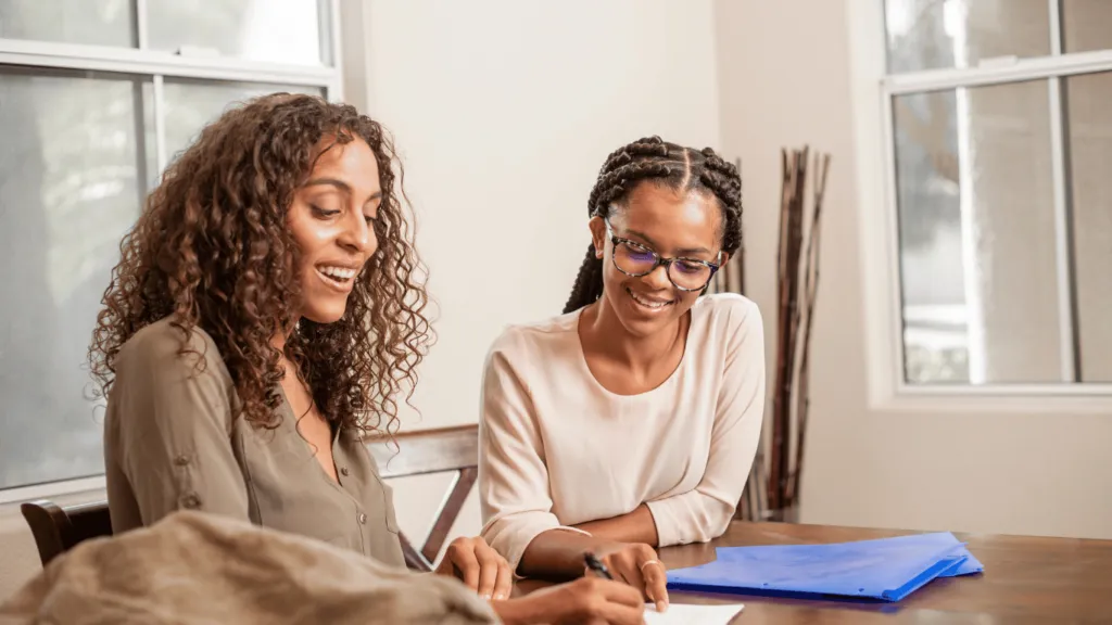 Teenager tutoring a woman at a table, showcasing easy ways for teenagers to make money through educational support.