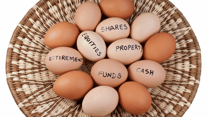 Canasta con huevos etiquetados como diferentes tipos de activos, ilustrando visualmente el concepto de Diversificar inversiones para reducir riesgos.